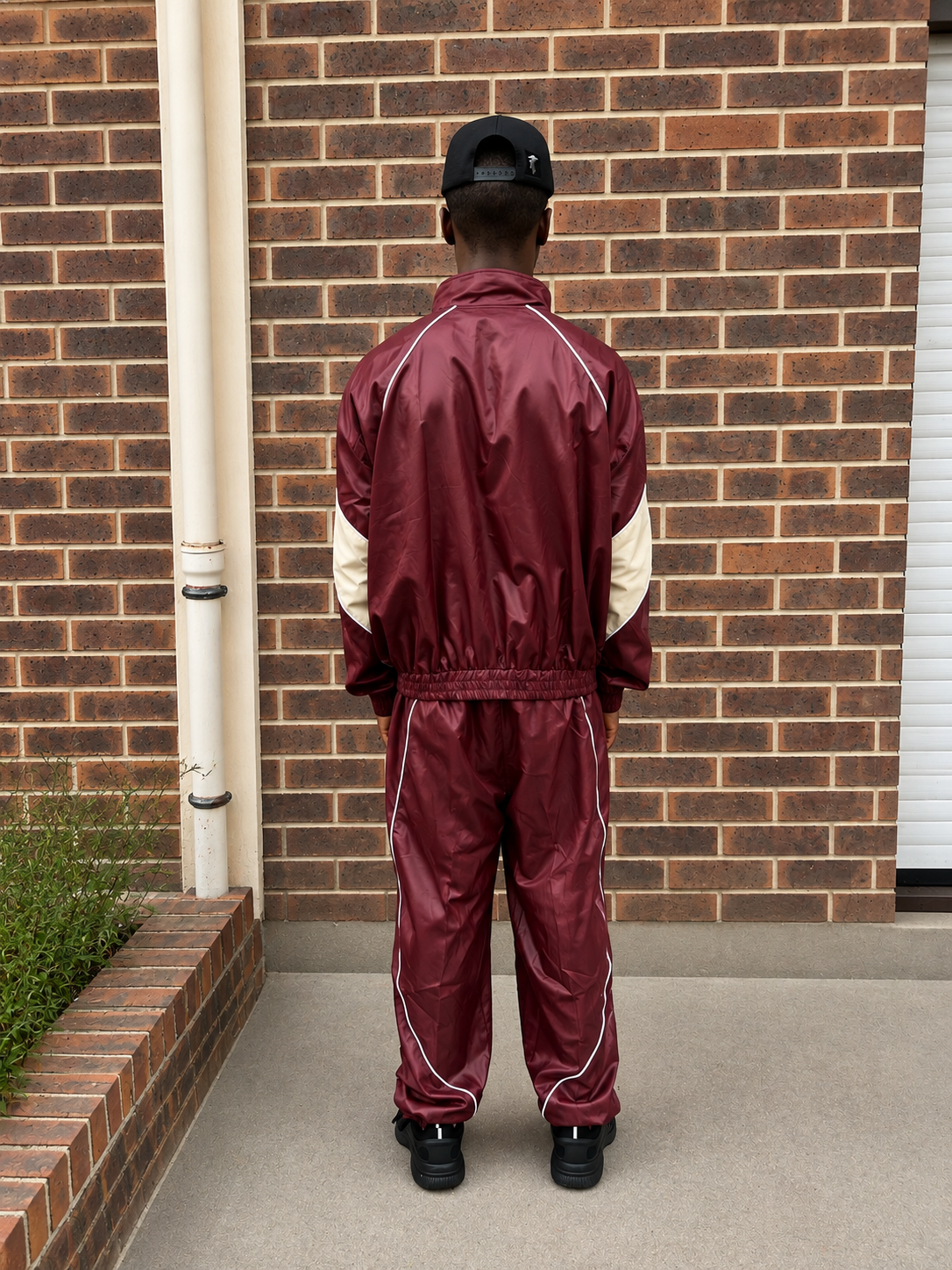 Homme portant le KIRA Tracksuit bordeaux avec veste zippée et pantalon assorti, collection streetwear KIRA Athletics.